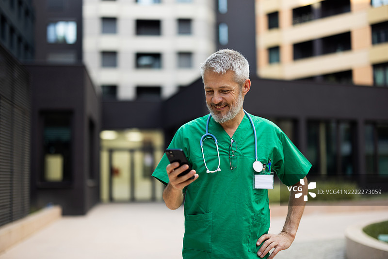 微笑的医生在医院外使用手机图片素材