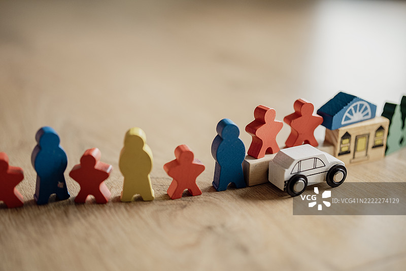 孩子的手在木地板上玩五颜六色的木制玩具，包括人物、汽车和交通标志。图片素材