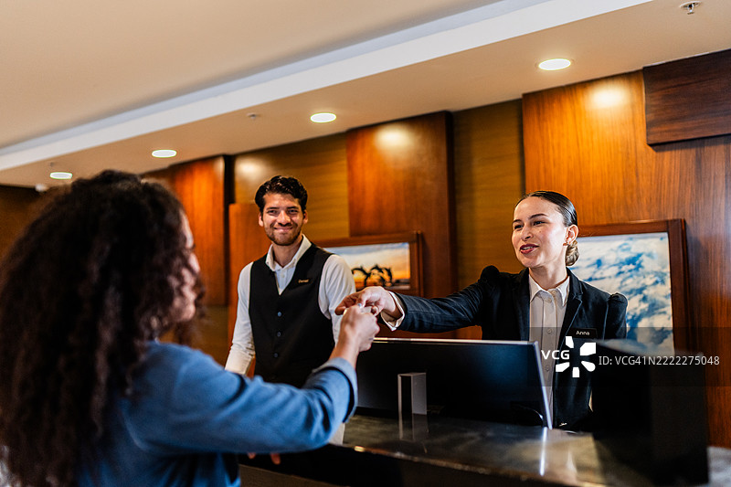 年轻的女接待员将房卡递给酒店客人图片素材
