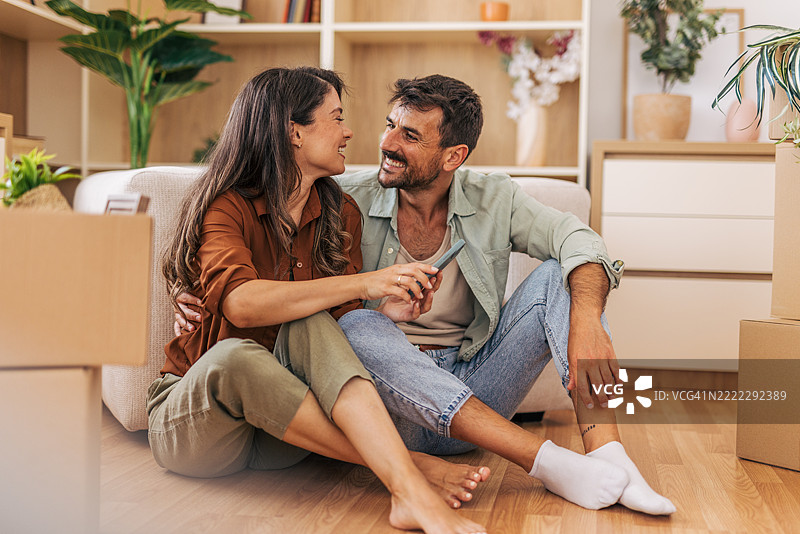 快乐的情侣在新家搬入后放松地坐在地板上图片素材