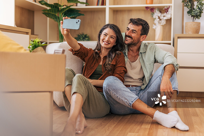 快乐的情侣在搬入新家时自拍图片素材