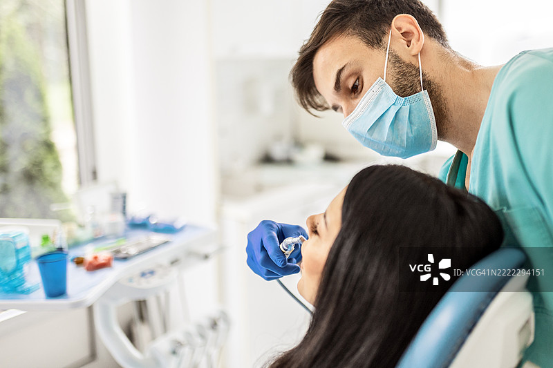 男牙医在诊所提供专业的牙科护理图片素材