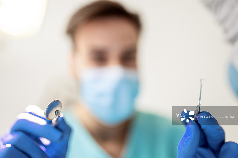 牙医准备好开始手术，手中拿着工具图片素材