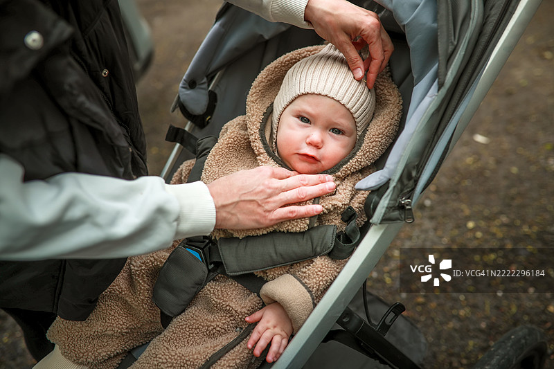 在秋天的公园里，妈妈正在给婴儿系好安全带。图片素材