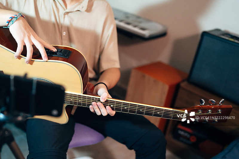 年轻音乐家用智能手机录制原声吉他演奏会图片素材