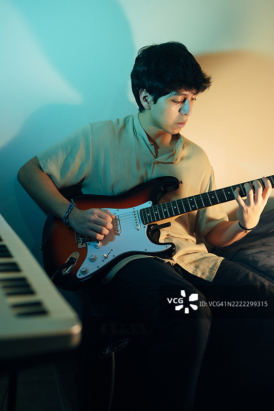 年轻音乐人在家庭工作室里弹电吉他图片素材