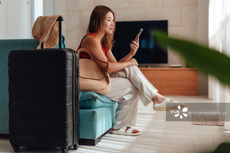 年轻的亚洲女性正在使用智能手机，为度假做准备图片素材