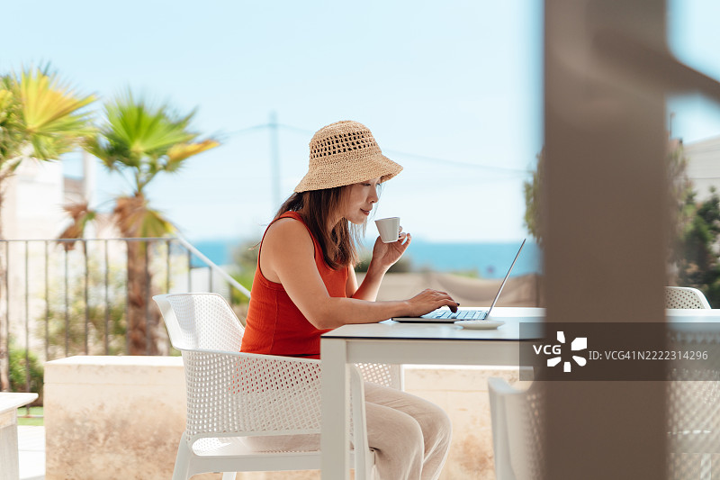 数字游牧者在度假别墅中享受假期，同时使用笔记本电脑工作图片素材