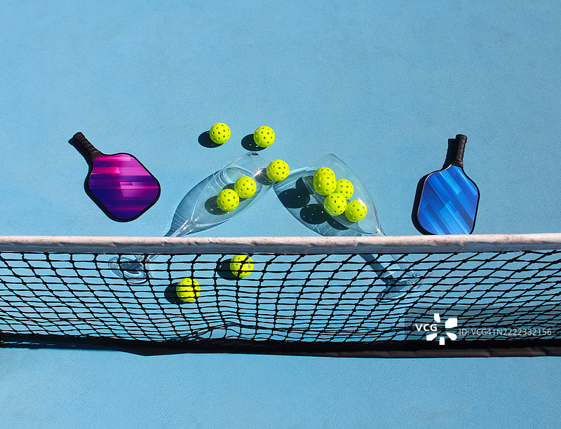 超大酒杯与球场上的泡菜球、泡菜球拍和网子在户外的场景图片素材