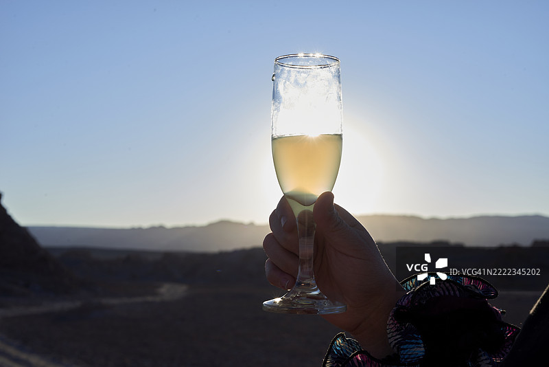 游客在阿塔卡马沙漠日落时举起一杯皮斯科酸酒图片素材