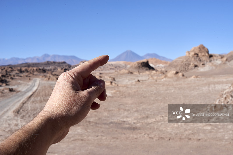 游客指着智利阿塔卡马沙漠的火山景观图片素材