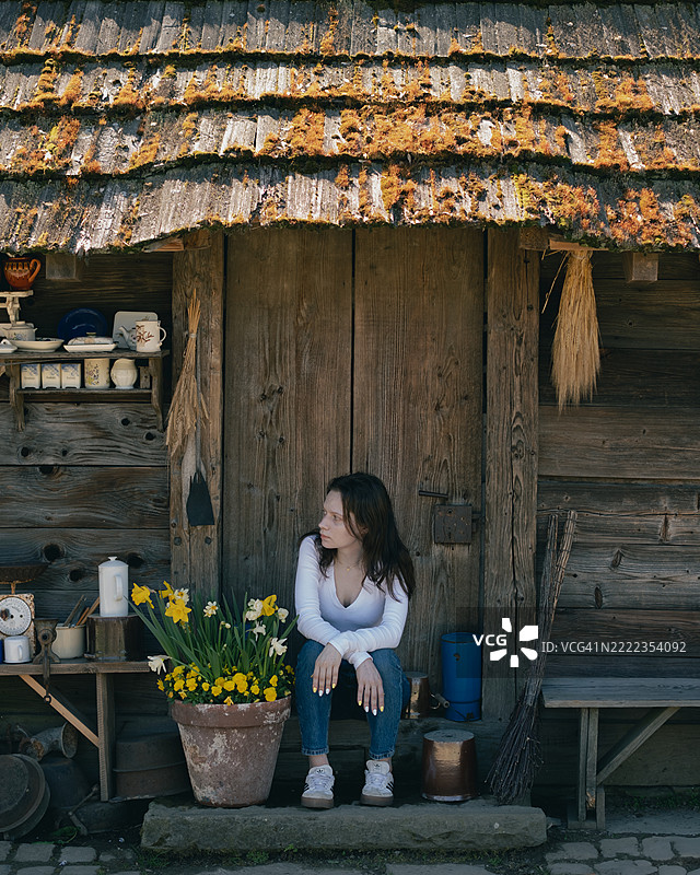 年轻女性坐在房子前，波兰图片素材