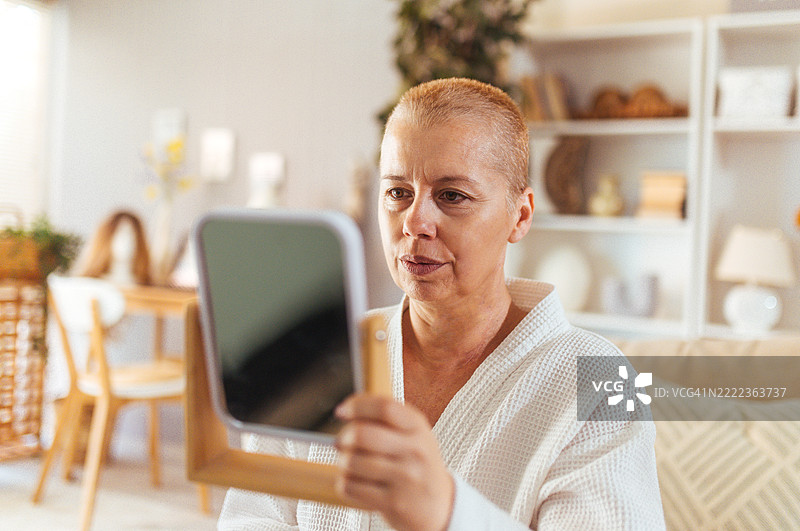 一位女性在化疗后剃头，展现出勇气和接受的时刻图片素材