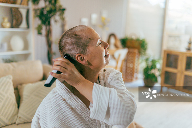 一位女性在化疗后剃头，展现出勇气和接受的时刻图片素材