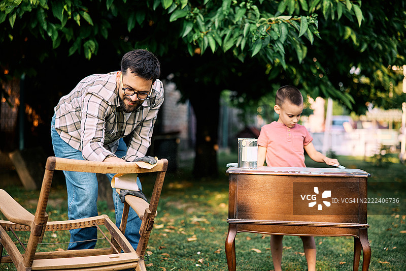 聪明的父子在后院进行家具修复。图片素材