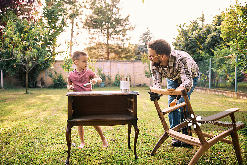 父亲和儿子在后院进行家具修复。图片素材
