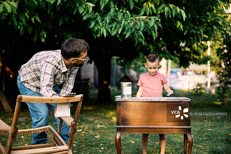 工匠和他的儿子在后院进行家具修复。图片素材