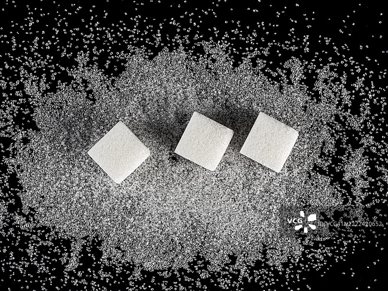 黑色背景上散落的糖块和糖粒。图片素材