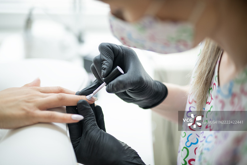 美甲师为指甲涂抹指甲油的特写镜头。图片素材