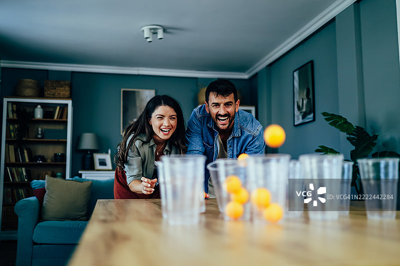 快乐的情侣在家里玩啤酒乒乓球图片素材
