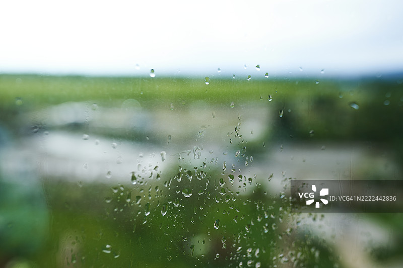 玻璃上的雨滴与模糊的绿色风景背景图片素材