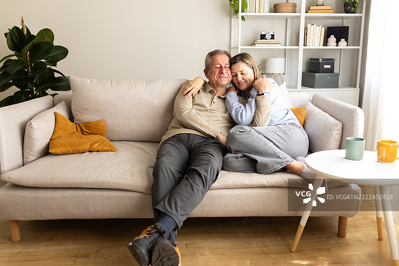 温馨客厅中，老年夫妇相拥坐在沙发上图片素材