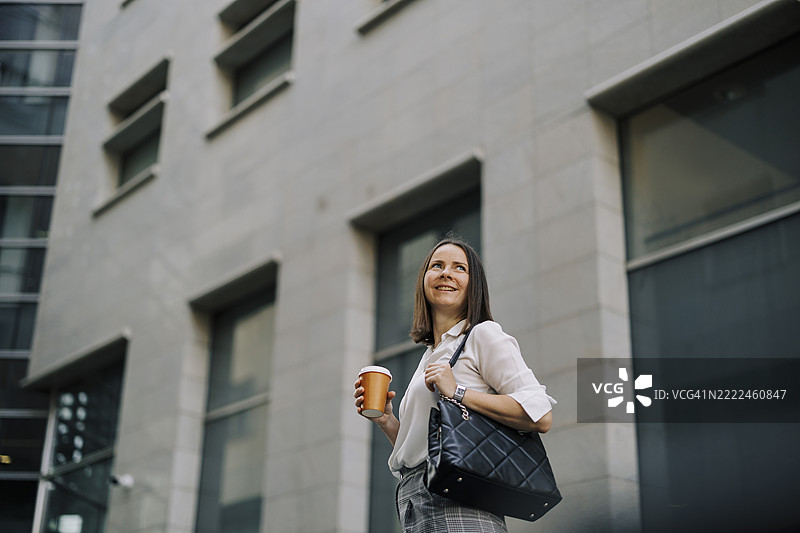美丽的女商人一边喝咖啡一边走路图片素材