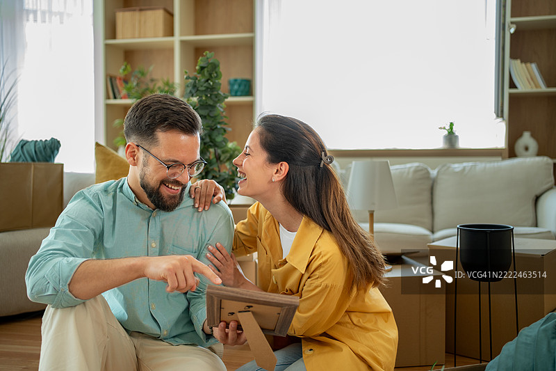 快乐的情侣在新家 unpacking 并查看照片图片素材