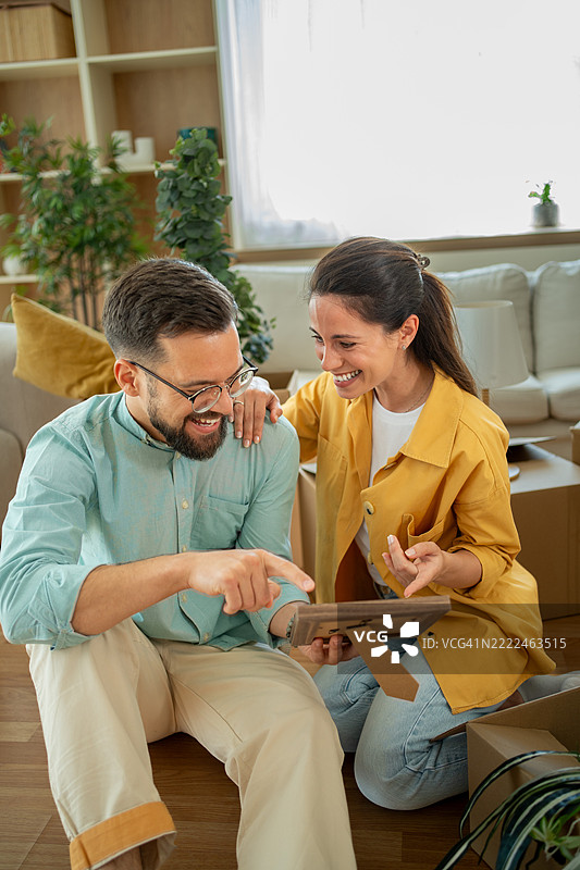 快乐的情侣在新家 unpacking，正在看着相框图片素材