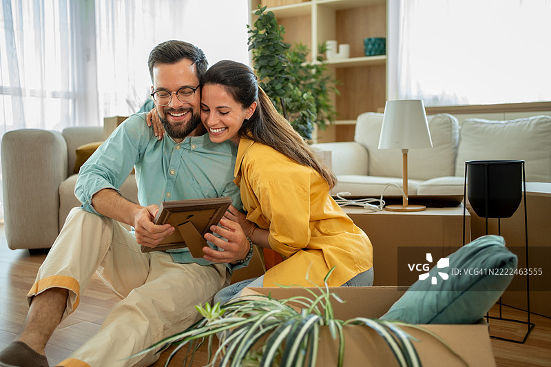 快乐的情侣在搬入新家时查看照片图片素材