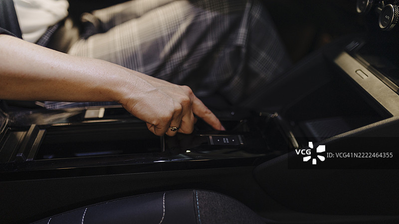 一位无法辨认的女性在开车时将手放在换挡杆上。图片素材