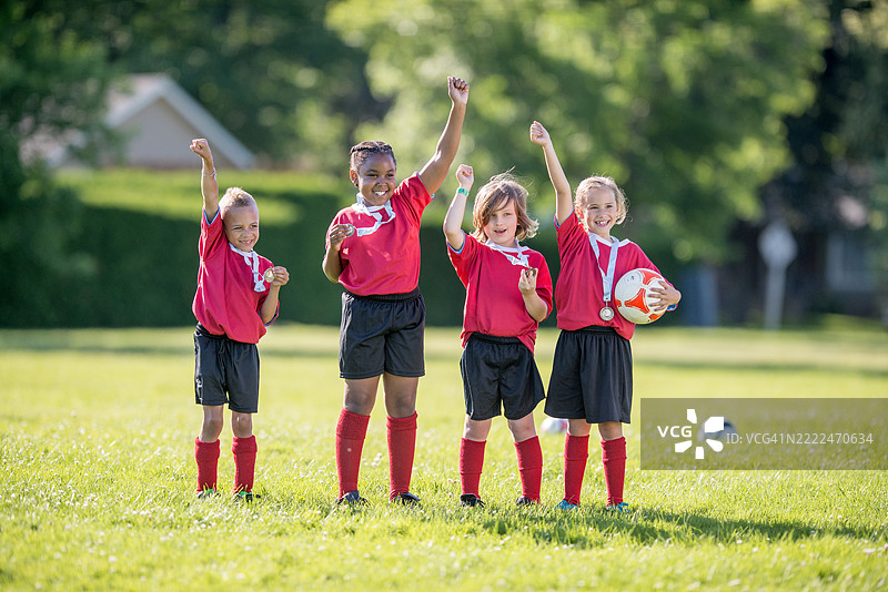 年轻足球队在阳光明媚的户外球场庆祝胜利图片素材