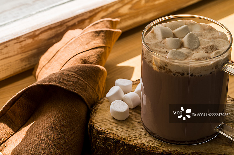 玻璃杯中的热巧克力配棉花糖，放在木窗台上图片素材