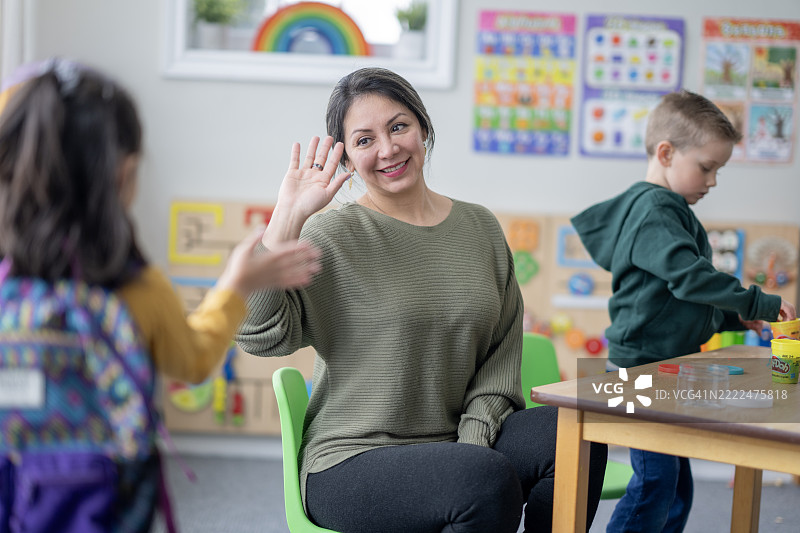 友好的老师在色彩缤纷的教室里与学生互动图片素材