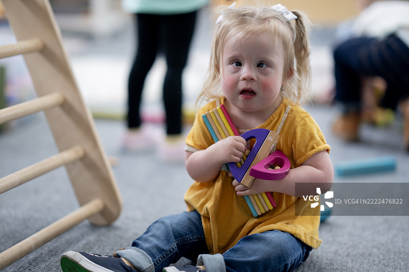 年轻女孩在充满活力的幼儿园环境中玩玩具图片素材