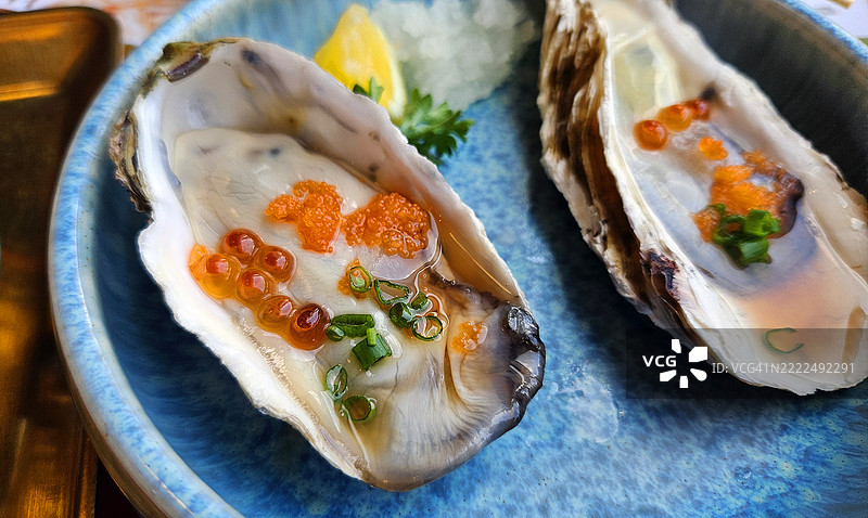 特写的塔斯马尼亚生蚝，上面放有鲑鱼卵、切片的葱和柠檬。图片素材