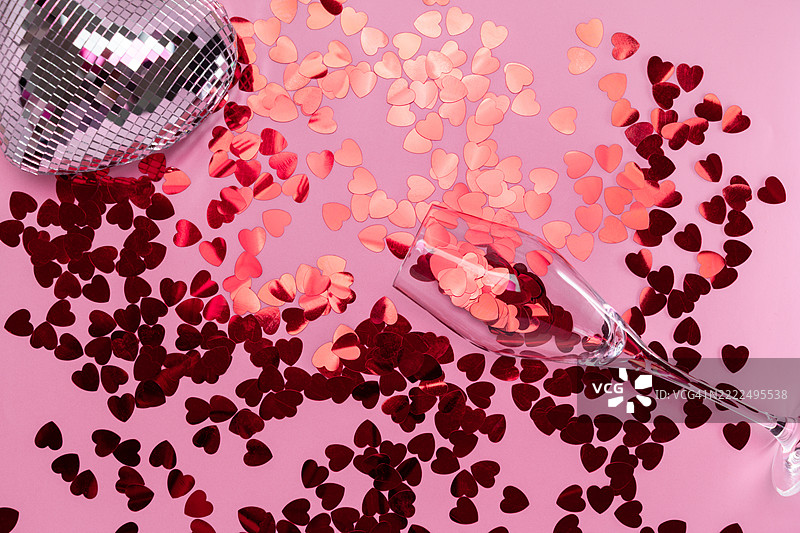 极简主义迪斯科心形香槟杯，盛满红色闪光粉，背景为粉色，法国图片素材