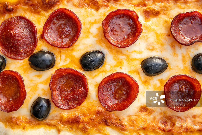 意大利快餐店的意大利香肠披萨特写，配有萨拉米香肠、黑橄榄和融化的奶酪图片素材