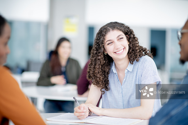微笑的学生在明亮的教室环境中与同伴合作图片素材