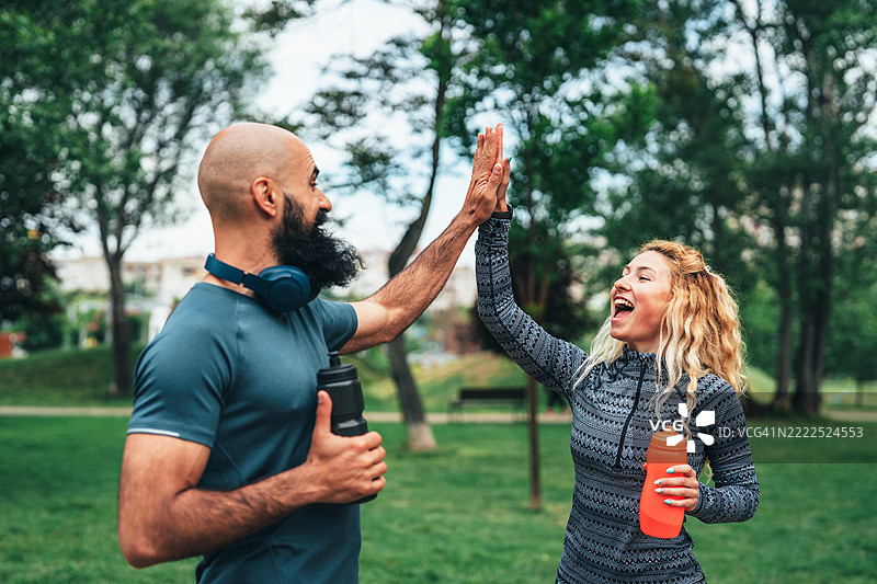 快乐的健身朋友们在户外锻炼后击掌庆祝图片素材