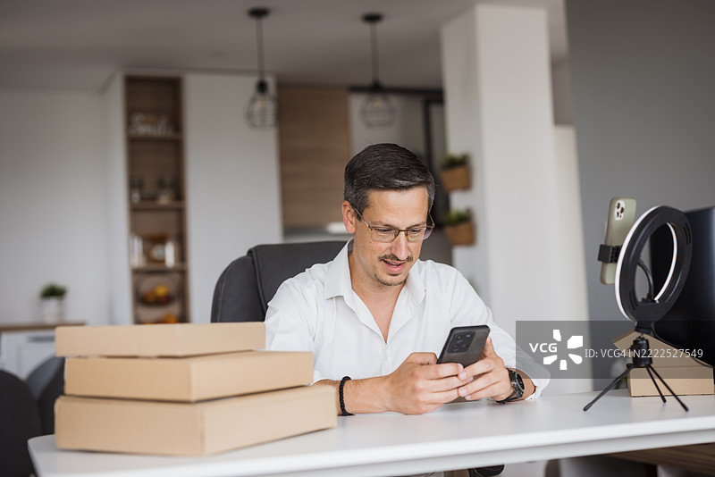 在家办公室中使用智能手机管理在线订单的企业家图片素材