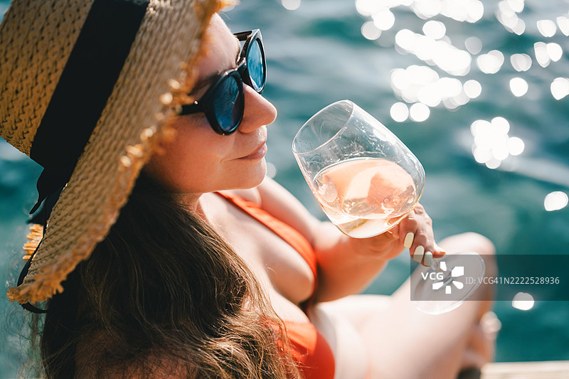 女人在水边放松时享受一杯葡萄酒图片素材