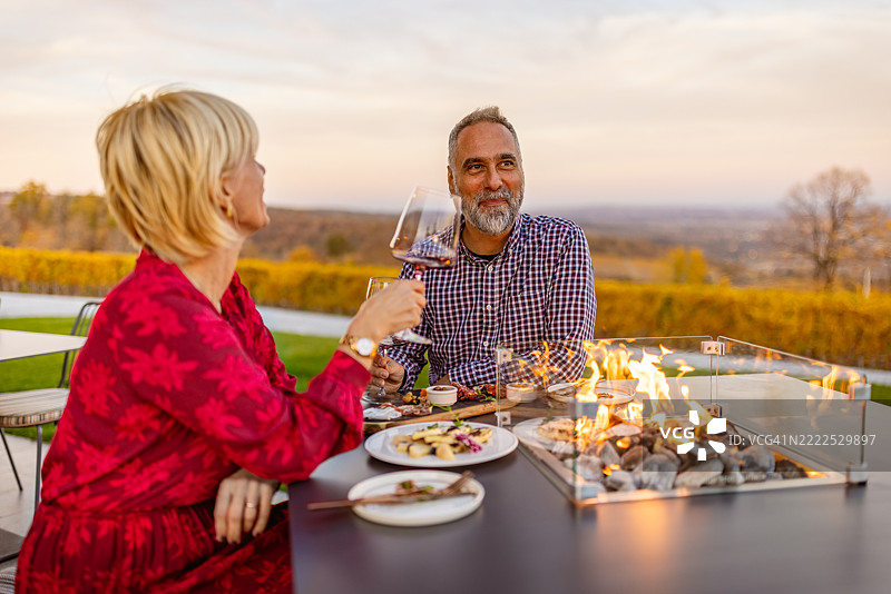 情侣在火坑旁享受户外晚餐，享有美丽的景色图片素材