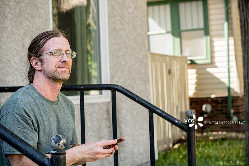 一位40多岁的白人男性在家门口用手机玩游戏图片素材