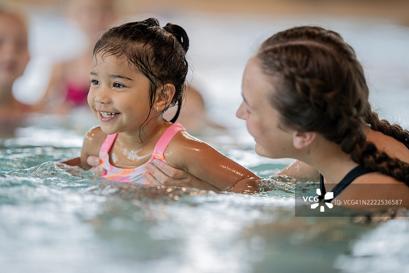 孩子在室内社区游泳池享受游泳课图片素材