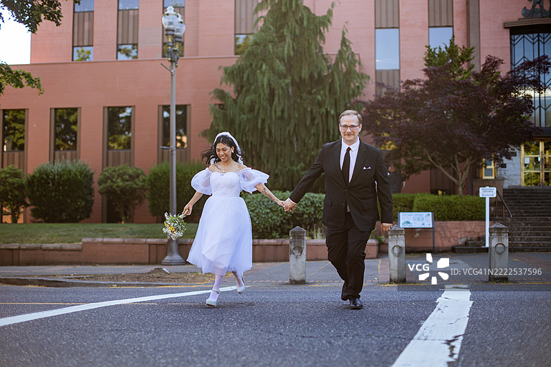 多种族的新娘和新郎在城市街道上奔跑图片素材