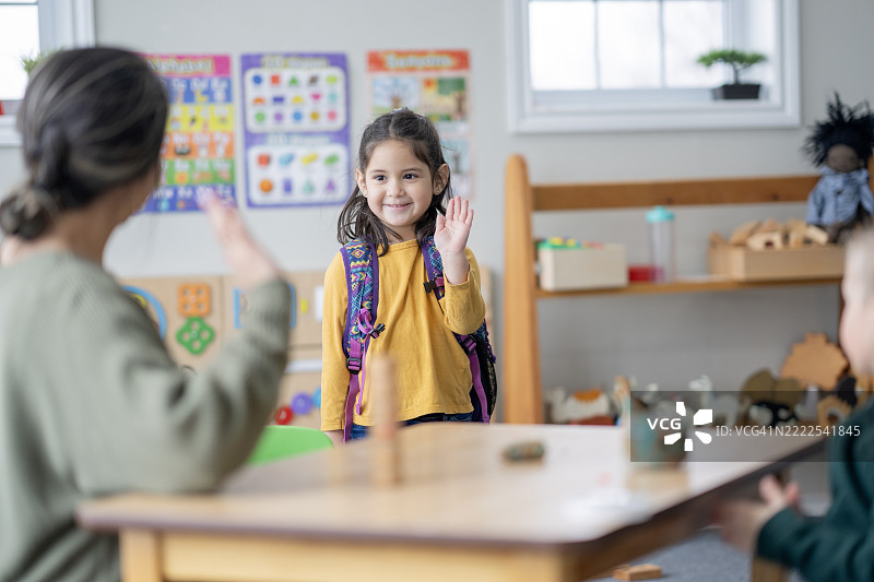 年轻女孩高兴地挥手向老师走进教室图片素材