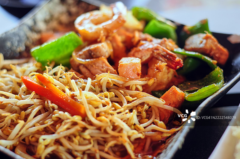 特写镜头展示了一盘色彩鲜艳的绿豆芽炒菜，盛放在深色方形盘子上。图片素材