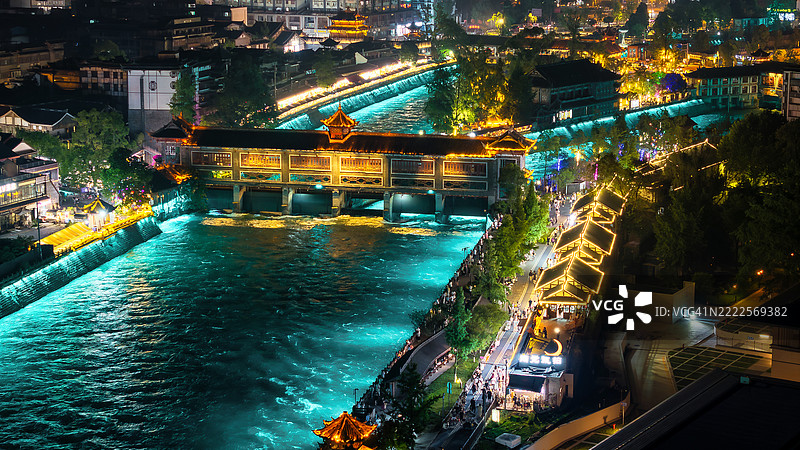 中国成都都江堰的古老桥梁和灯光照亮的河流的夜间航拍景观。闪烁的灯光映衬出这一著名旅游景点的文化之美和活力。图片素材