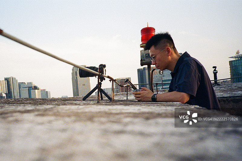一名中国男子在屋顶拍摄城市风景的胶卷照片图片素材